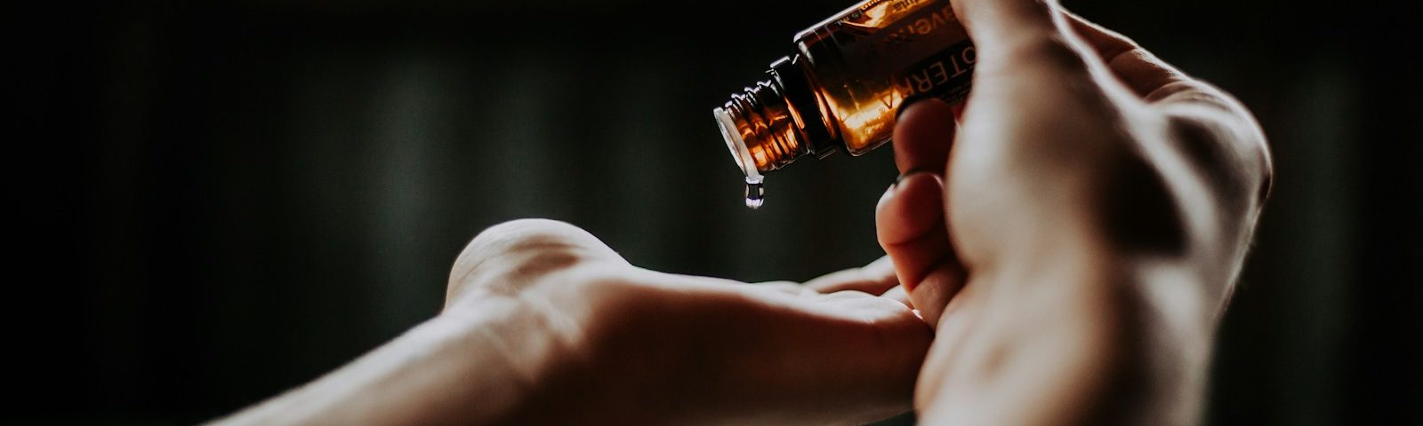 person holding amber glass bottle