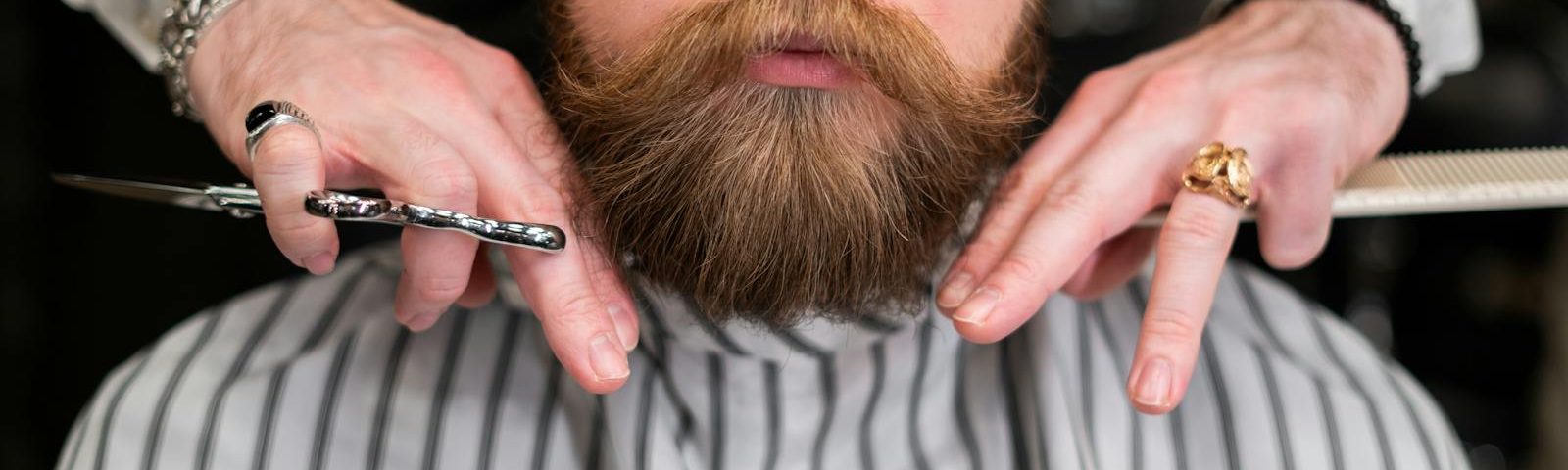 A stylish bearded man receiving precision grooming at a barbershop.