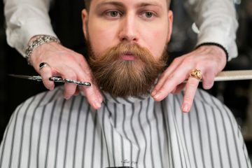 A stylish bearded man receiving precision grooming at a barbershop.