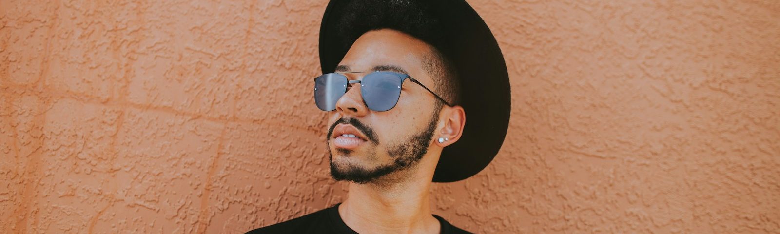 man leaning on brown wall