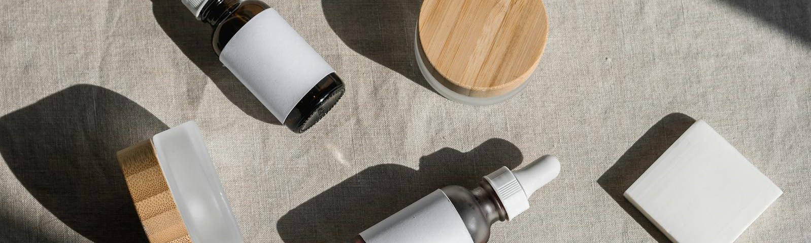 A minimalist flat lay of cosmetic bottles and jars on a linen cloth, perfect for beauty product presentations.