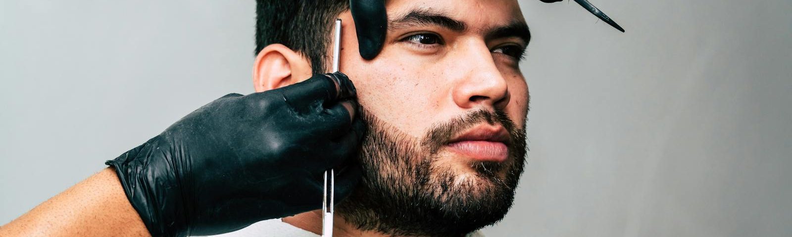 Man receiving a precise beard trim in a barbershop, showcasing expert grooming skills.