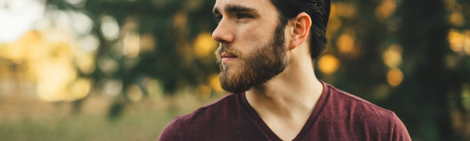 man wearing maroon V-neck t-shirt in forest