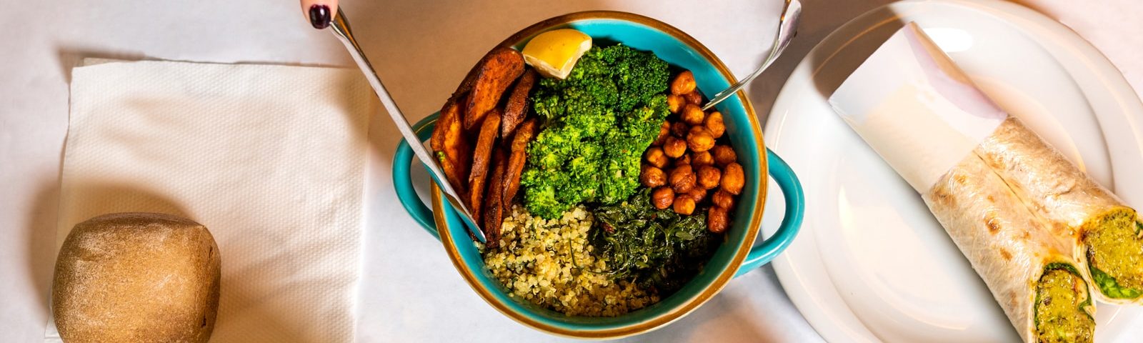 person holding silver spoon and blue ceramic bowl with food