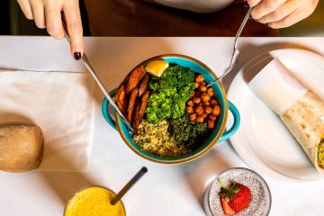 person holding silver spoon and blue ceramic bowl with food